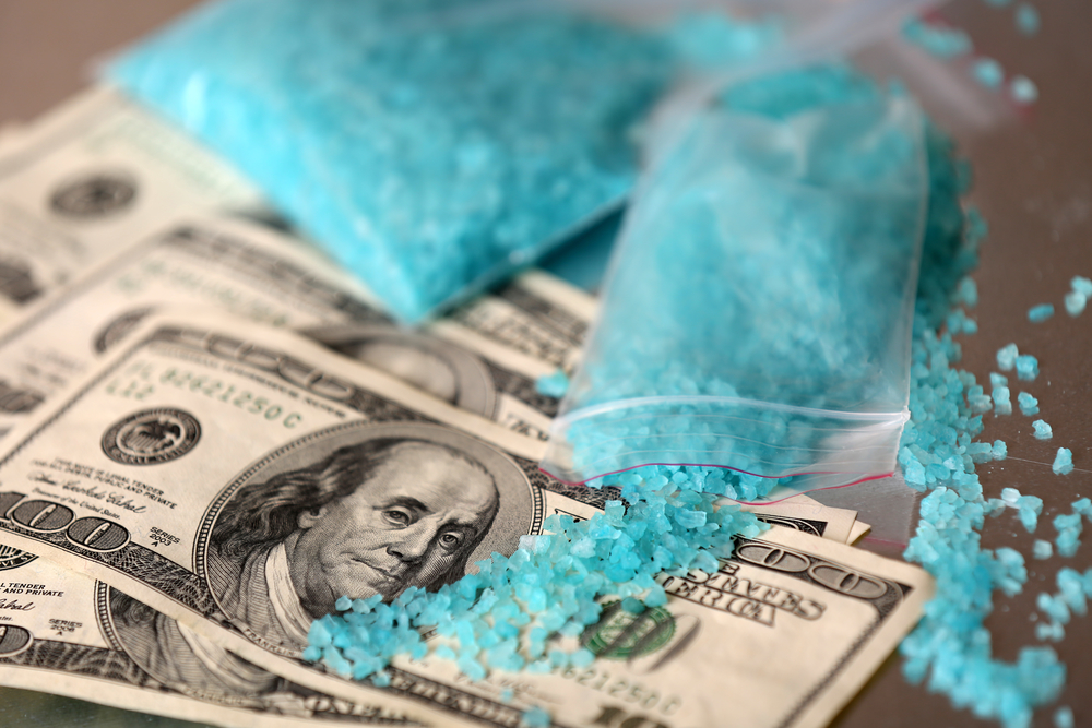 Drug laboratory: blue methamphetamine and money on table close up