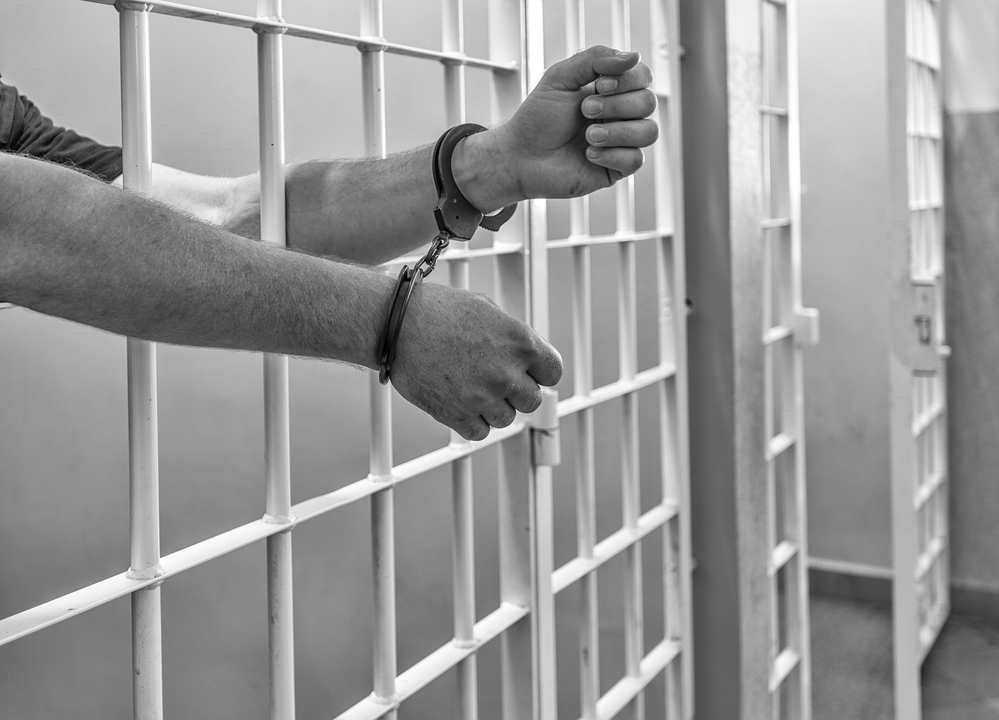 Prisoner in handcuffs locked in a cell.