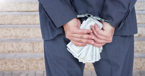 Businessman hands in handcuffs holding US dollars