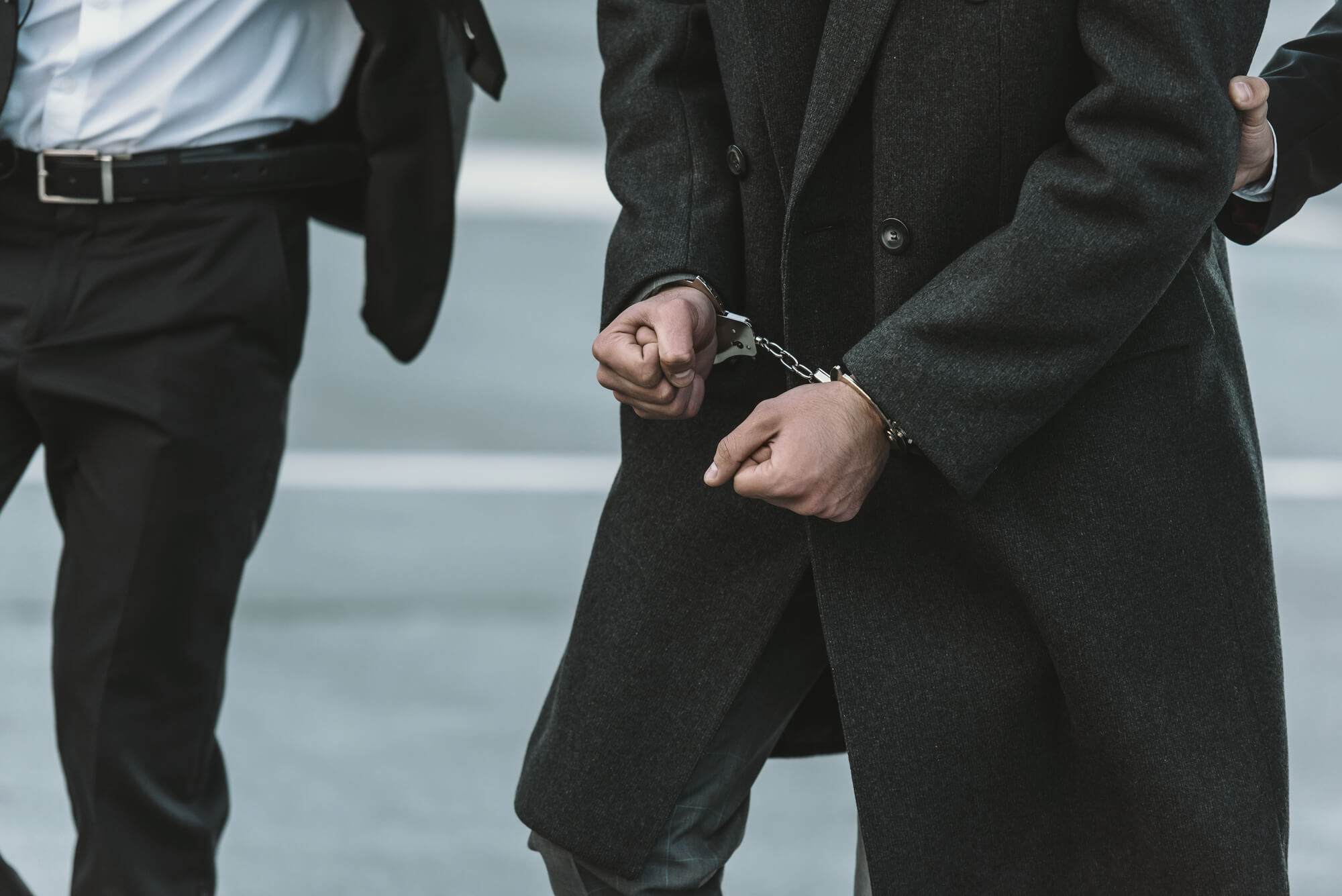 person in handcuffs being escorted