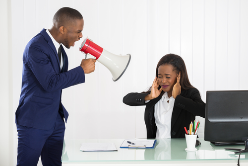 Boss Shouting At Young Businesswoman Through Loudspeaker In Office