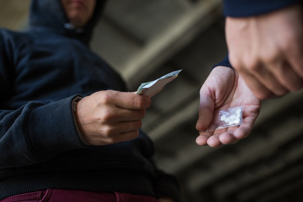 drug dealing, crime, addiction and sale concept - close up of drug addicts buying doses on the street