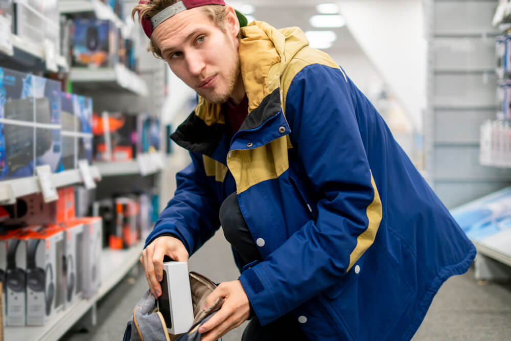 young man shoplifting a gadget from a store
