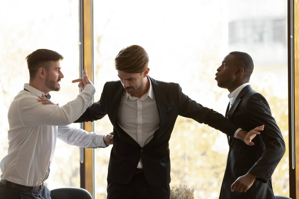 Male colleague set apart angry diverse business men coworkers argue fighting at corporate office meeting, mad employees quarreling shouting having conflict at work, racial hatred harassment concept