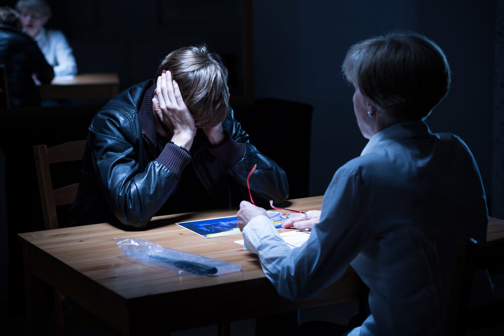 Young offender covering ears during police interrogation