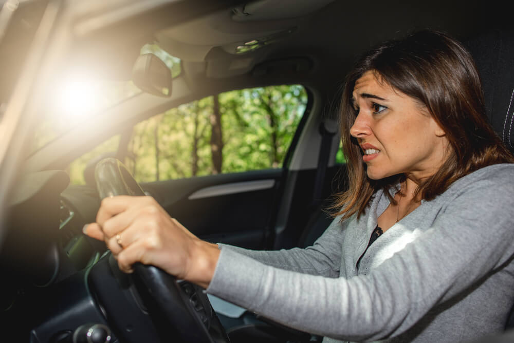 Scared caucasian woman driving car and risking a car crash. Without insurance