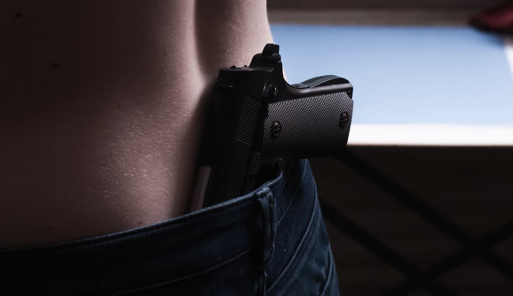 close-up of a person with a gun in his belt, illegal possession of weapons