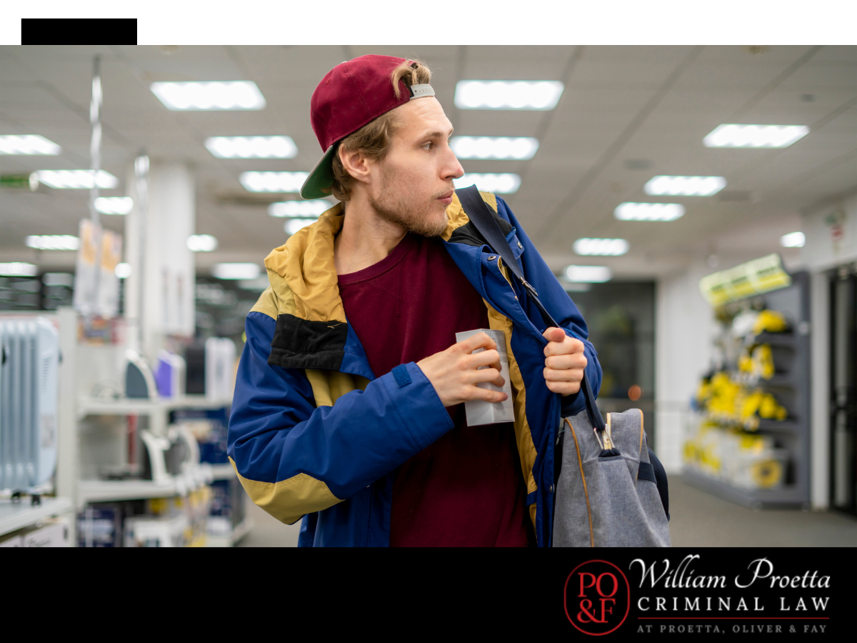 A young man concealing a store item under his jacket as a way of shoplifting.