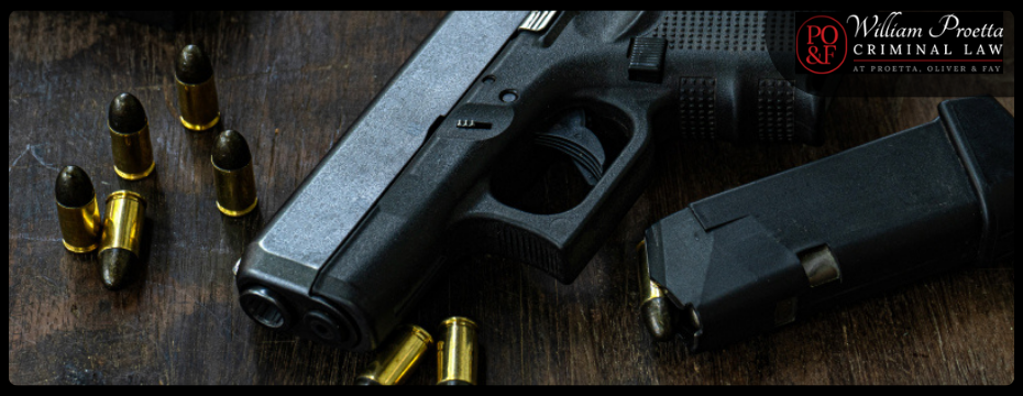 A handgun and a magazine are placed on a wooden table, representing New Jersey Weapons Charges