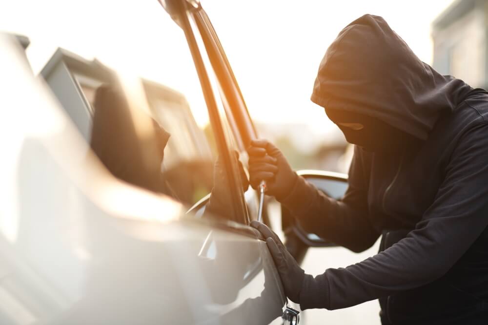 Hooded person breaking into a car for an auto theft lawyer in Hudson County page